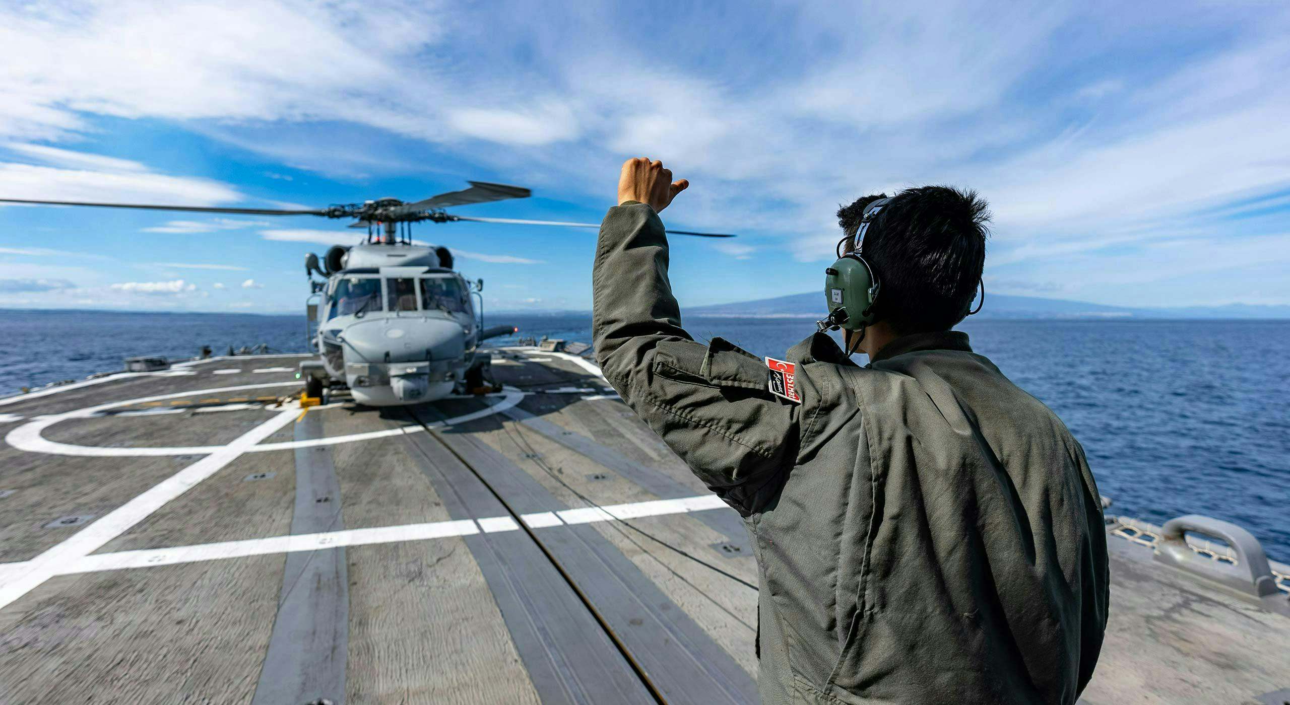 A Turkish naval crewman signals to a Seahawk helicopter during exercise Dynamic Manta. Mediterranean Sea, February 2024.