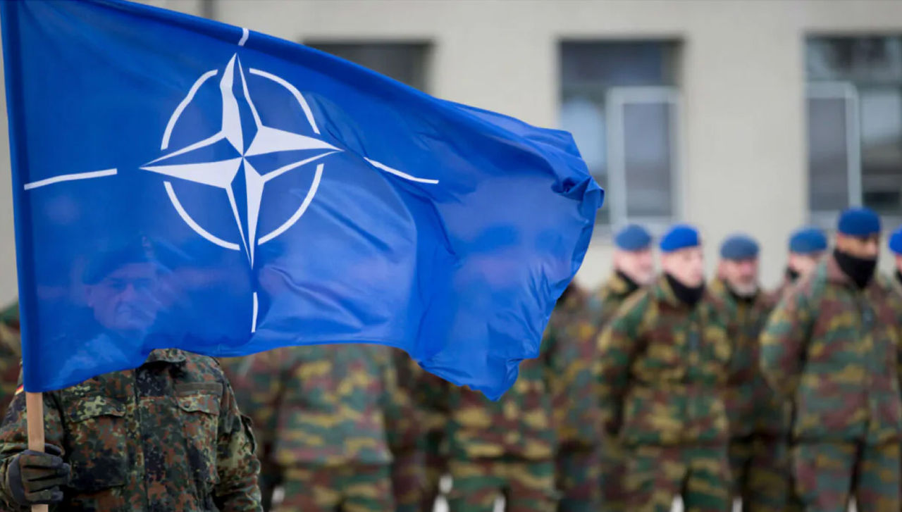 A German soldier holds the NATO flag at the Alliance’s multinational battlegroup in Rukla, Lithuania. © Kay Nietfeld / dpa picture alliance 